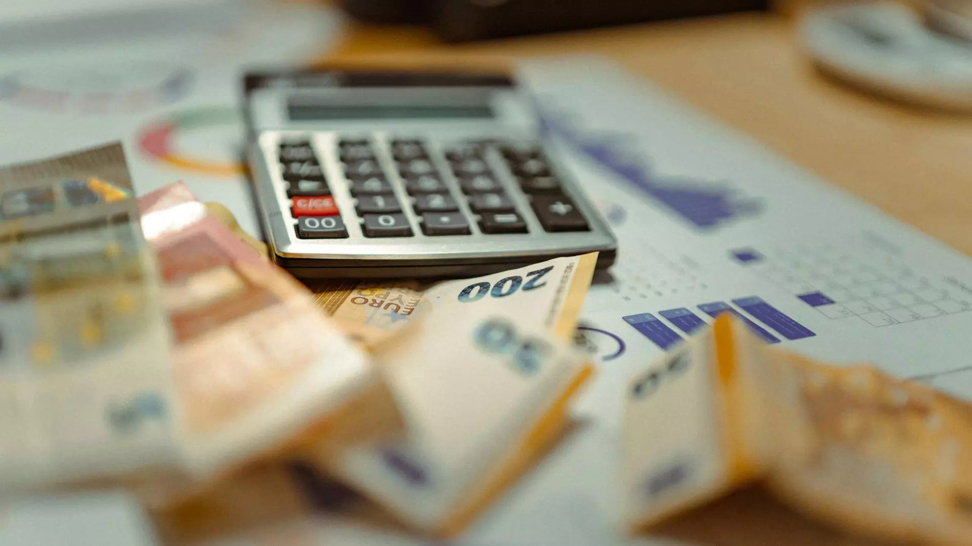 Calculatrice avec des billets et des graphiques sur une table.