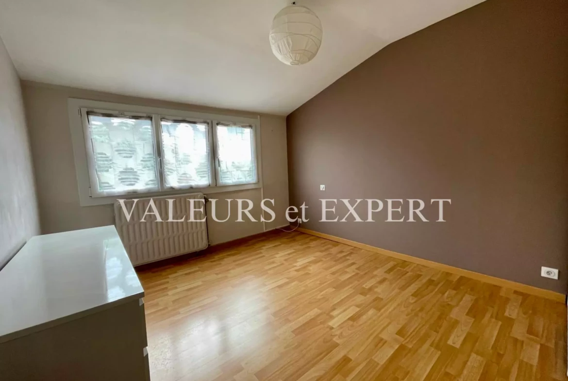 Chambre spacieuse et lumineuse avec parquet et grande fenêtre.