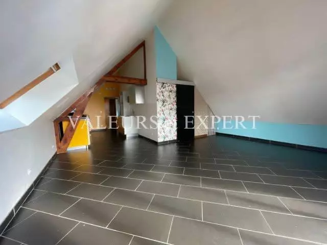 Salon lumineux avec poutres apparentes et carrelage moderne dans un appartement à Templemars.